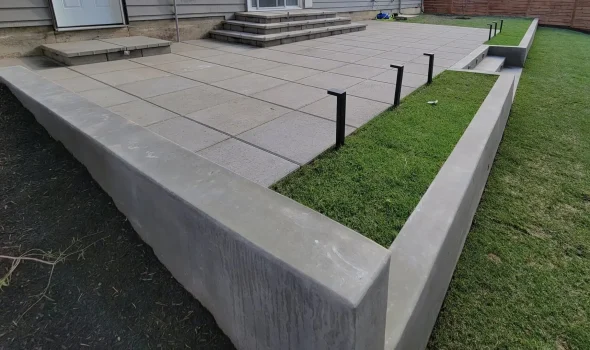 Durable Retaining Wall Construction With Clean Concrete Edges Durable retaining wall construction showing a smooth concrete wall supporting a raised lawn area